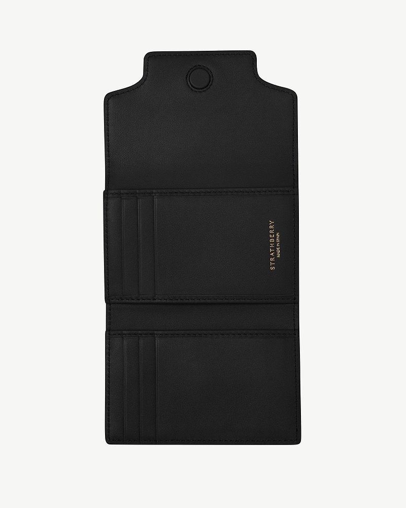 Black Multrees trifold wallet open showing card slots and gold Strathberry logo