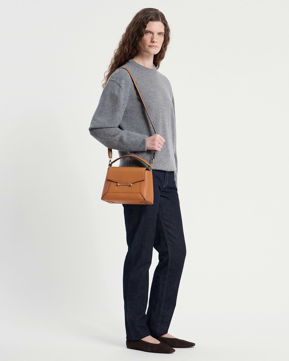 Model wearing a grey jumper and jeans carrying a honey mosaic bag over her shoulder.