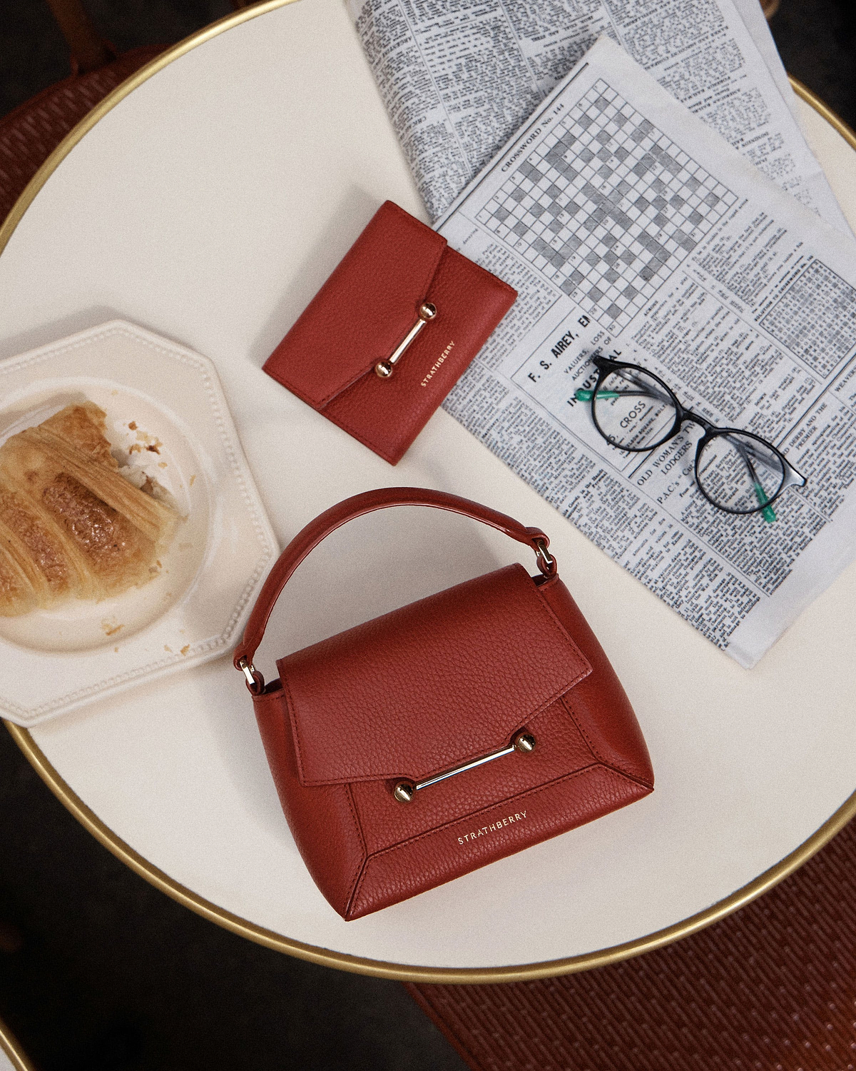 Strathberry Levanto red Mosaic Nano top-handle bag with matching wallet on a table.