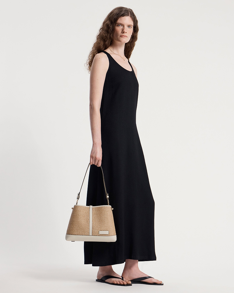 Model carrying a vanilla and natural raffia Lana Hobo bag at her side.