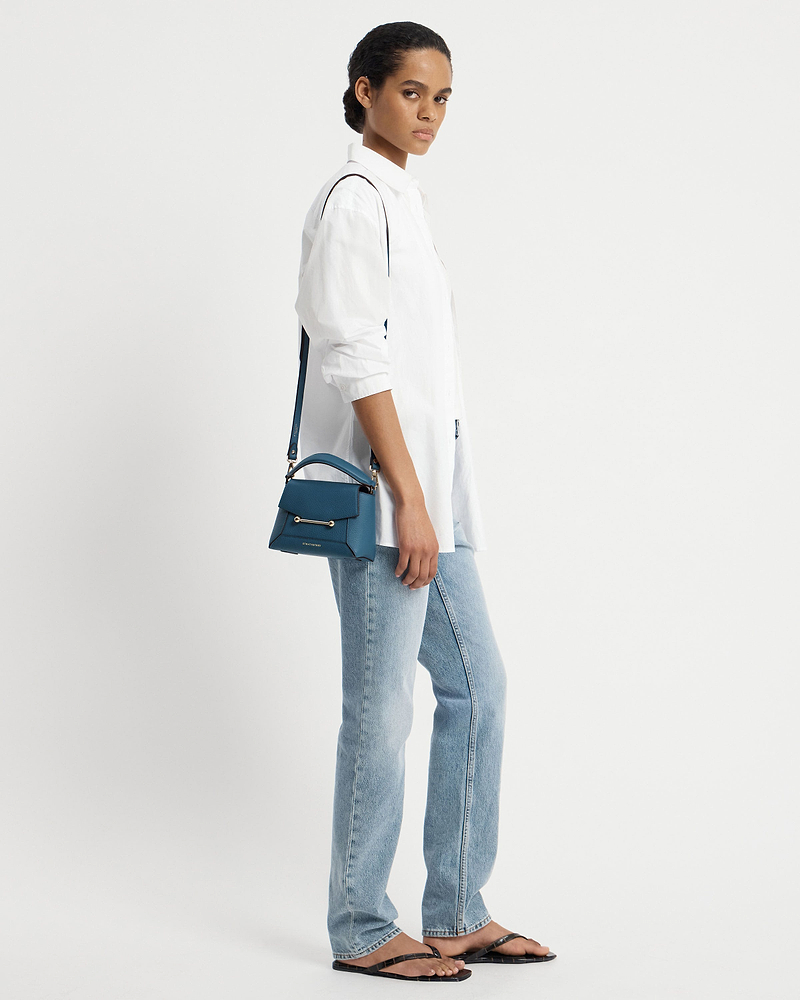 Model in white shirt and jeans carrying loch blue Mosaic Nano shoulder bag.