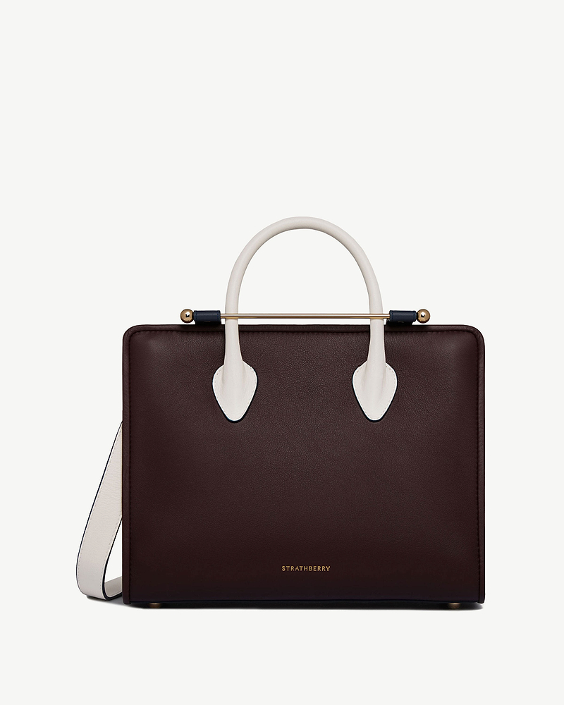 Strathberry midi tote in burgundy with vanilla handles, navy accents and gold bar.