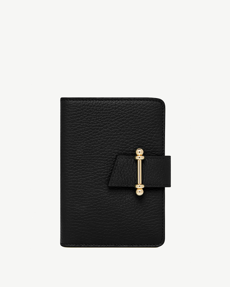 Black grained leather passport holder with gold bar clasp on front strap.