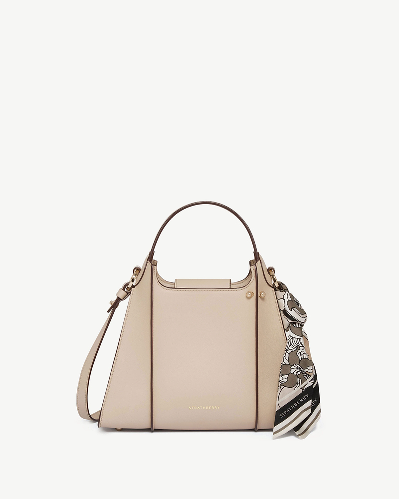 Strathberry Arkshell bag in oat with top handle, shoulder strap and patterned scarf.