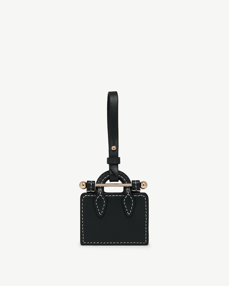 Black tote charm with contrast white stitching and gold bar detail.