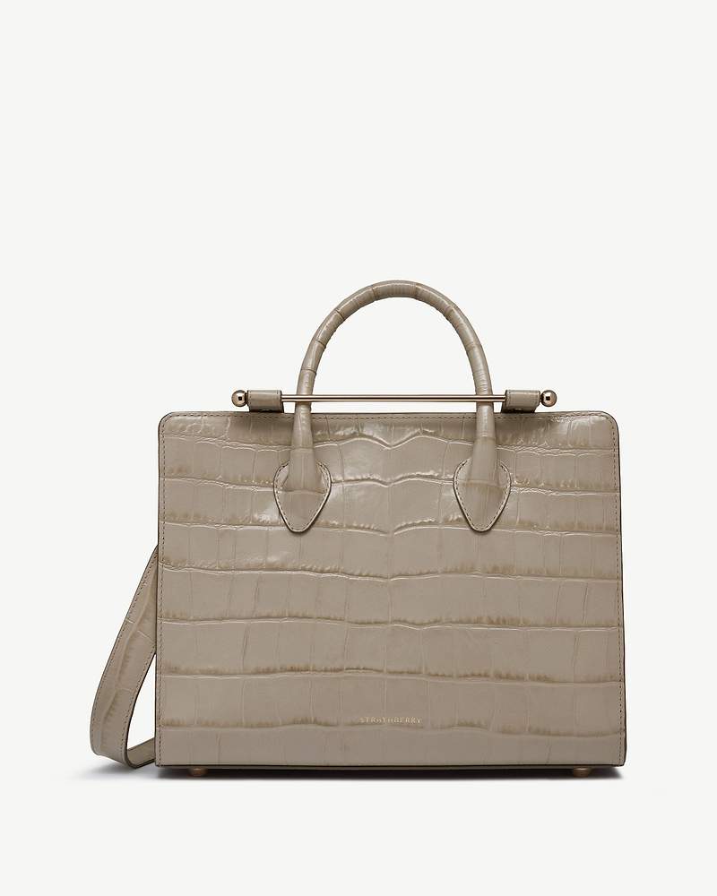 Strathberry midi tote in croc-embossed leather with top handles, shoulder strap, gold bar.