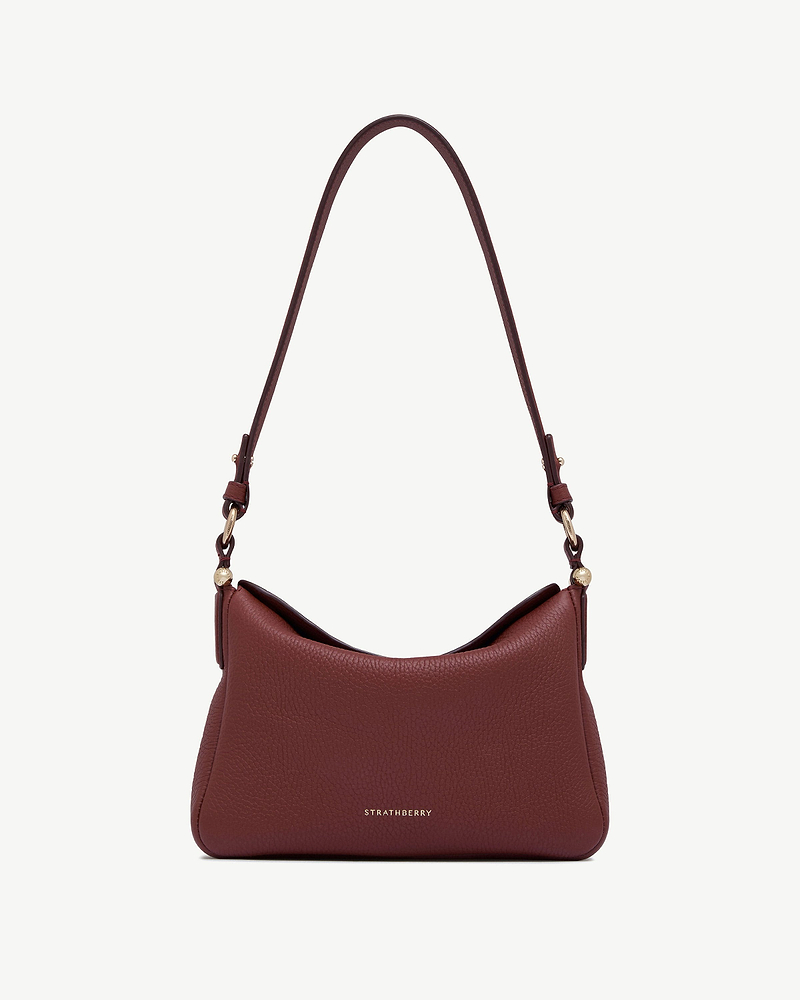 Oxblood pebbled leather shoulder bag with curved strap and gold Strathberry logo.