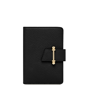 Black leather passport holder with gold bar strap closure, pebbled texture.