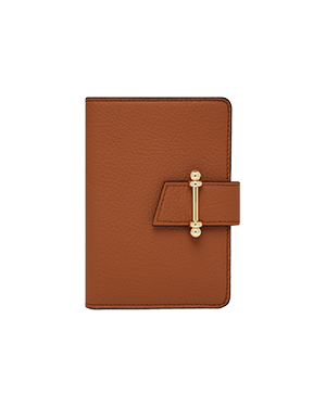 Tan pebbled leather passport holder with gold bar clasp closure and stitching