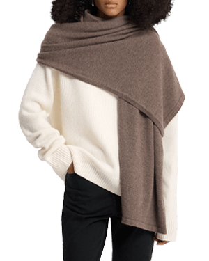 Model wearing otter-coloured travel wrap draped over cream jumper and black trousers