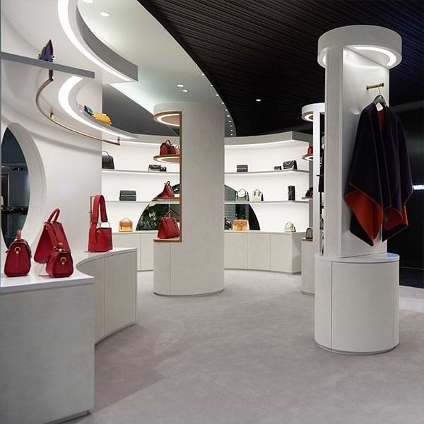 A room filled with lots of white shelves filled with purses
