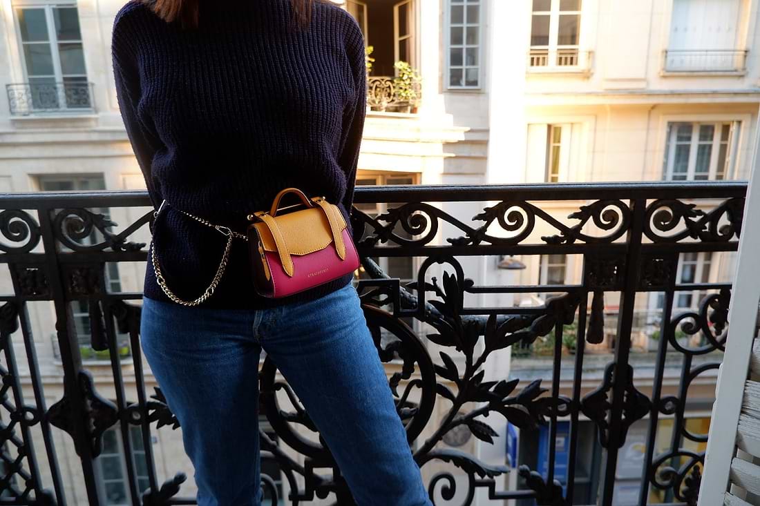 A woman standing on a balcony holding a purse