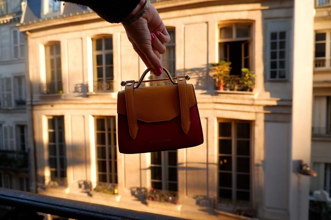 A hand holding a brown and red purse