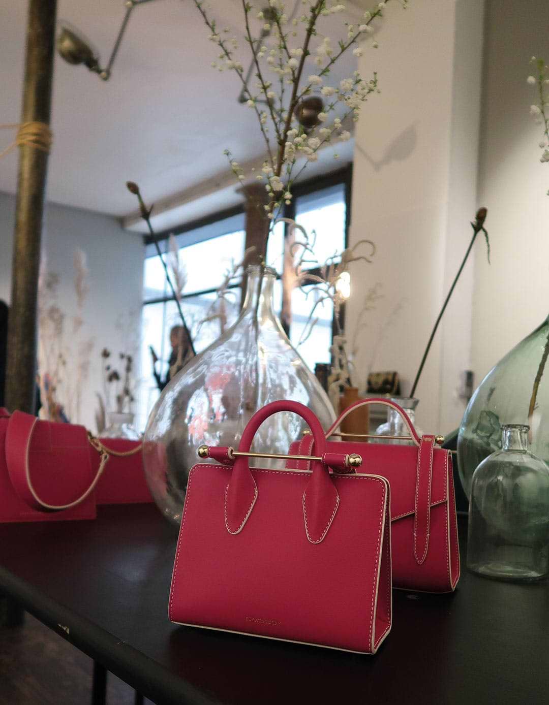 A table with three bags and vases on it