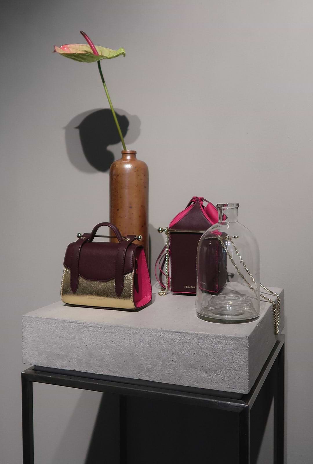 A vase with a flower and two purses on a table