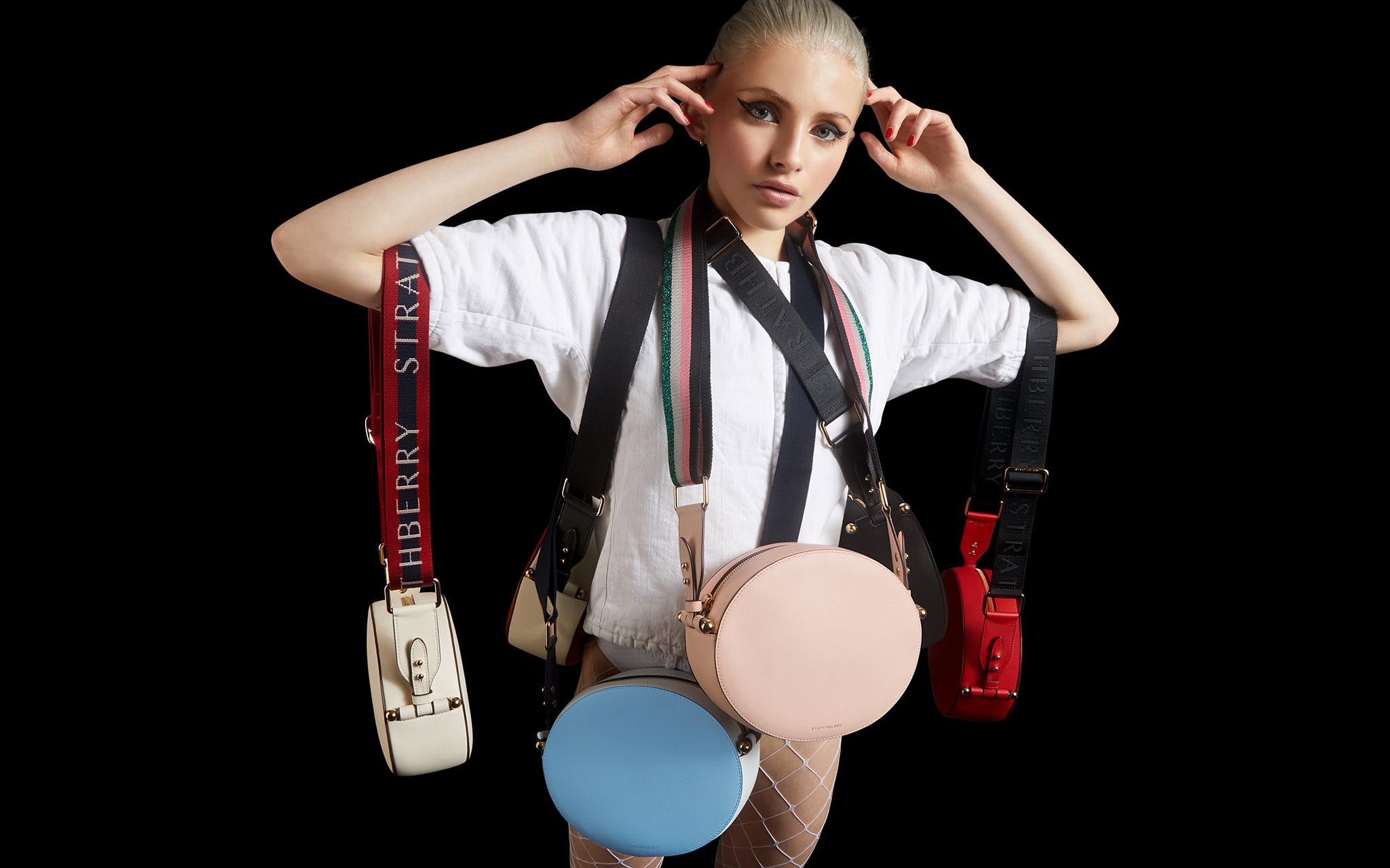 A woman in a white shirt and suspenders holding a camera
