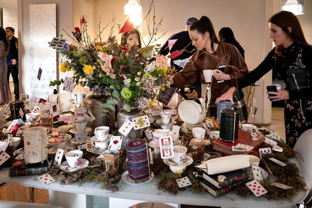 A group of women standing around a table covered in cards and vases