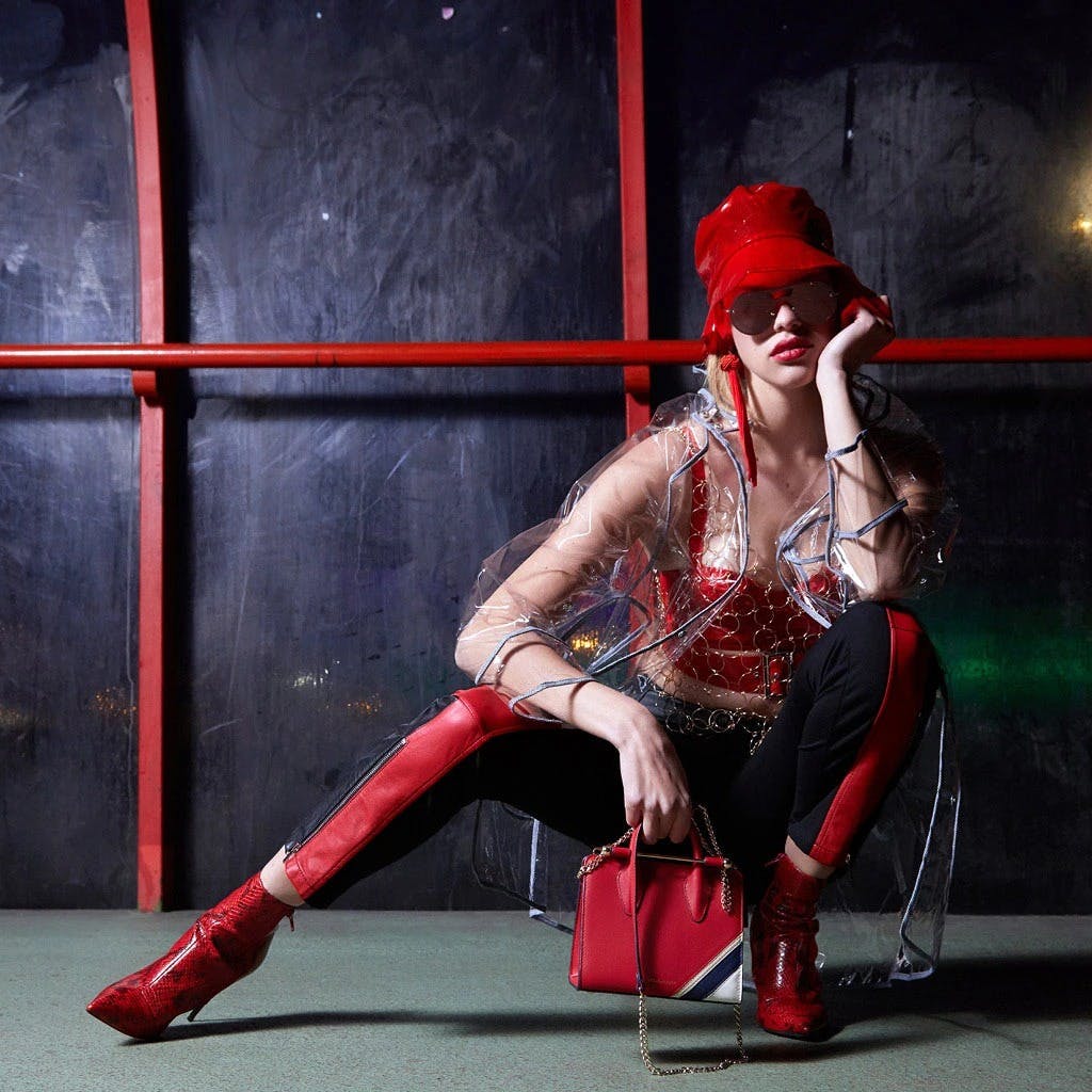 A woman sitting on a chair holding a red purse