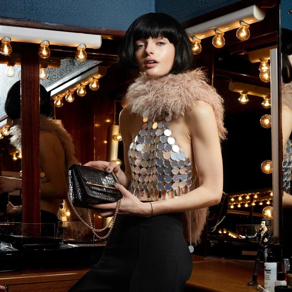A woman is holding a purse in front of a mirror