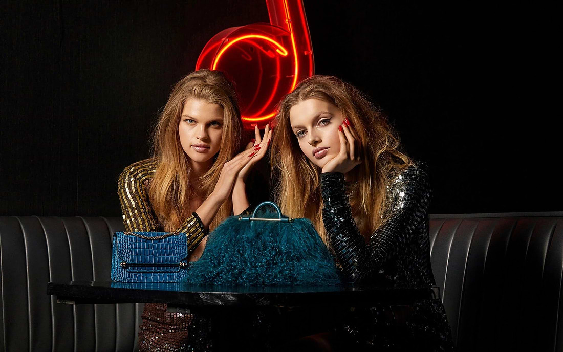 Two beautiful young women sitting next to each other at a table