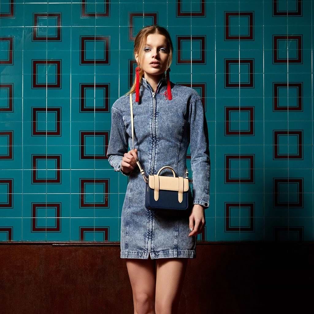 A woman standing in front of a wall holding a purse