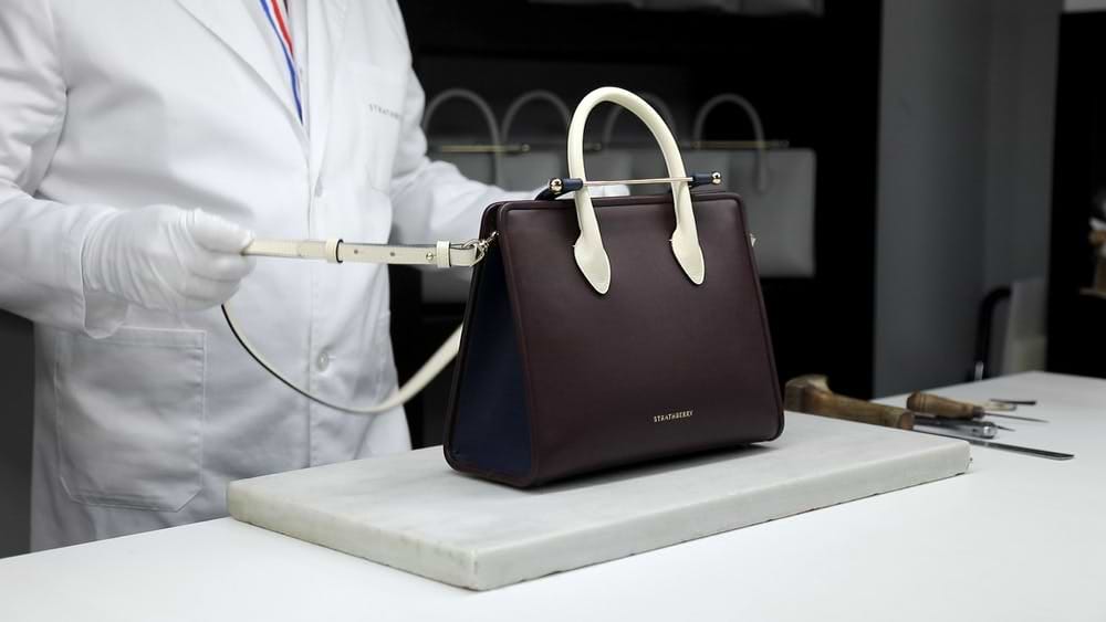 A person in a lab coat holding a handbag