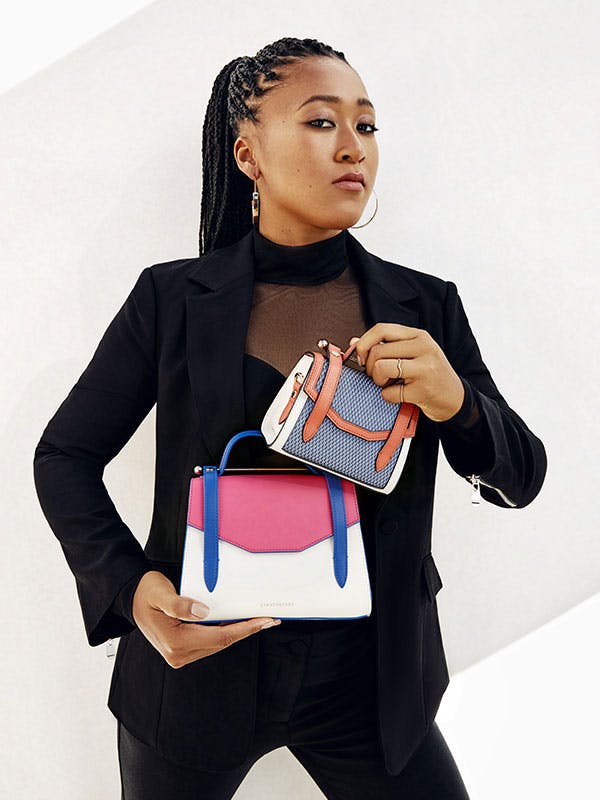 A woman in a black jacket holding a multicolored purse