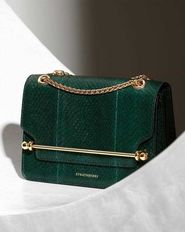 A green handbag with a gold chain hanging from it