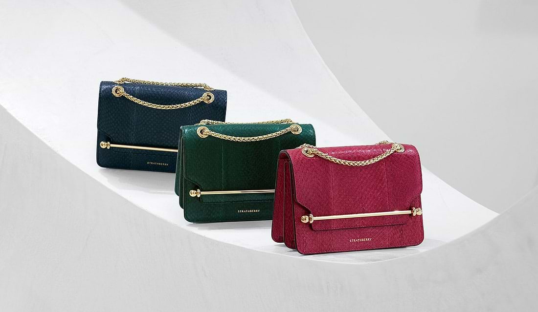 A row of three purses sitting on top of a white surface