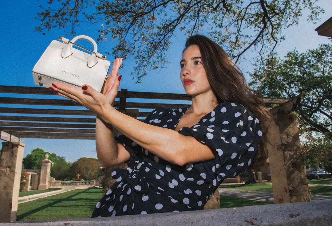 A woman holding a white purse in her hands