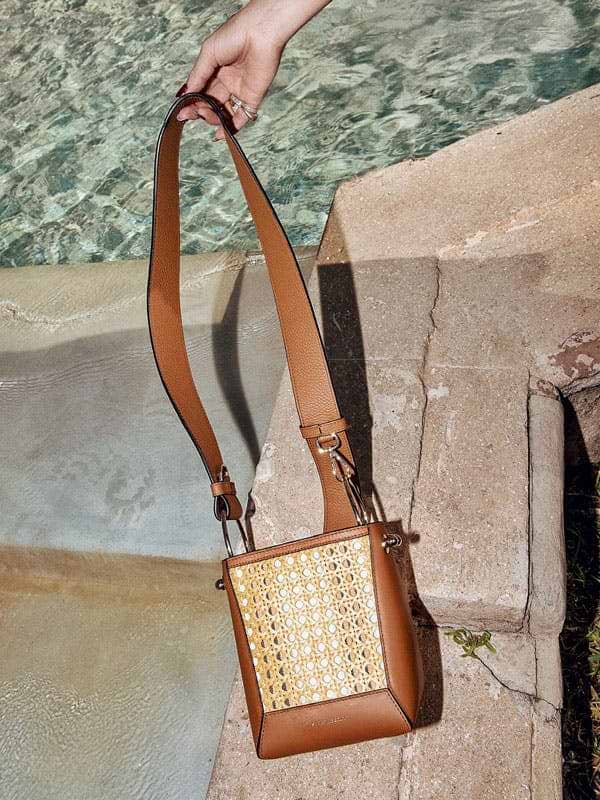 A woman's hand holding a brown purse by a pool