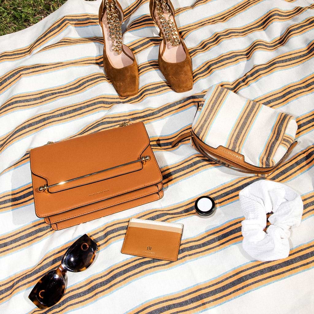A woman's purse, shoes, sunglasses, and a purse on a blanket