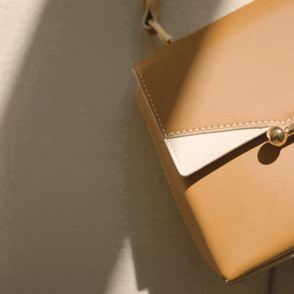 A tan purse sitting on top of a white table