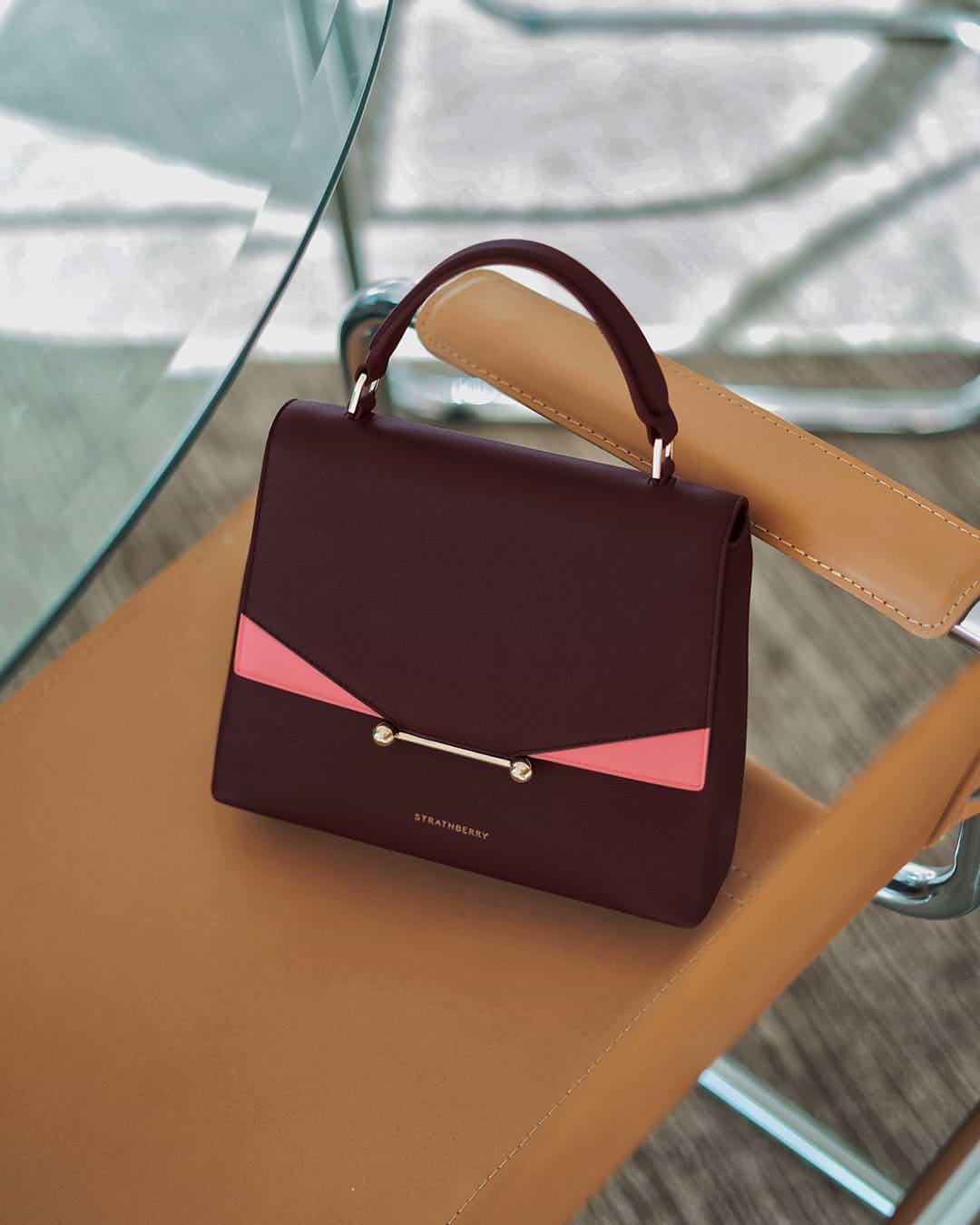 A brown and pink purse sitting on top of a table