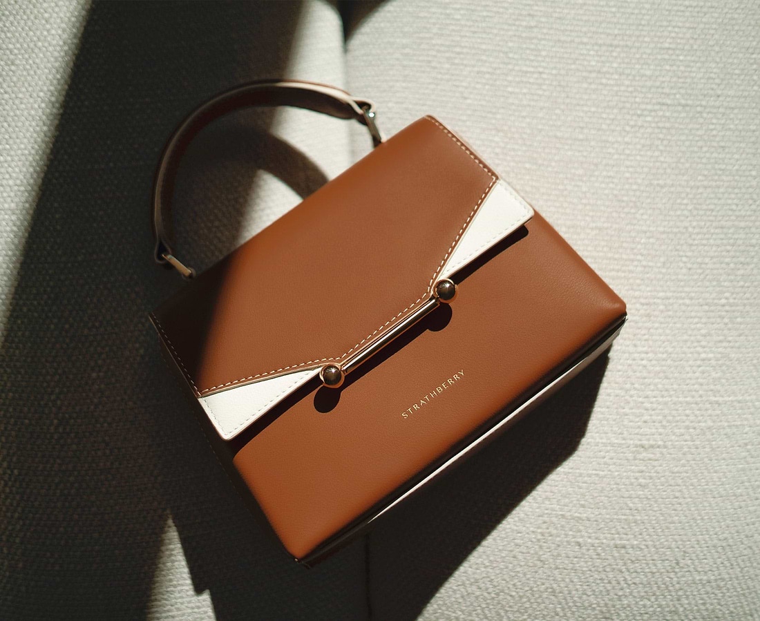 A brown and white purse sitting on top of a couch