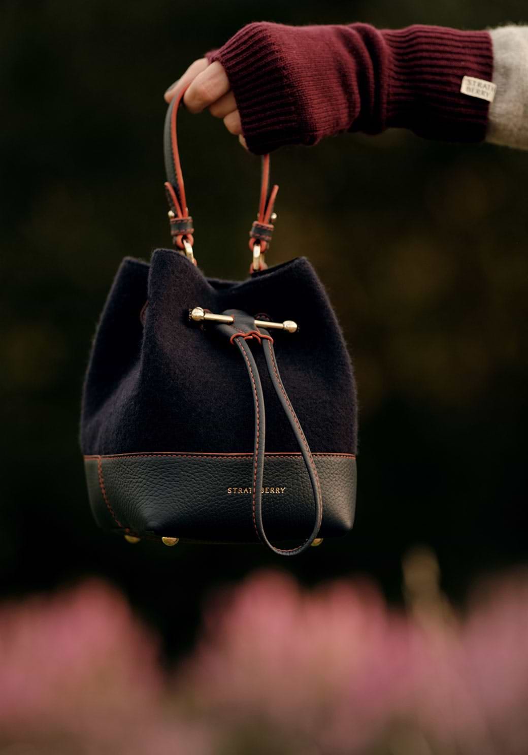 A hand holding a black and brown purse