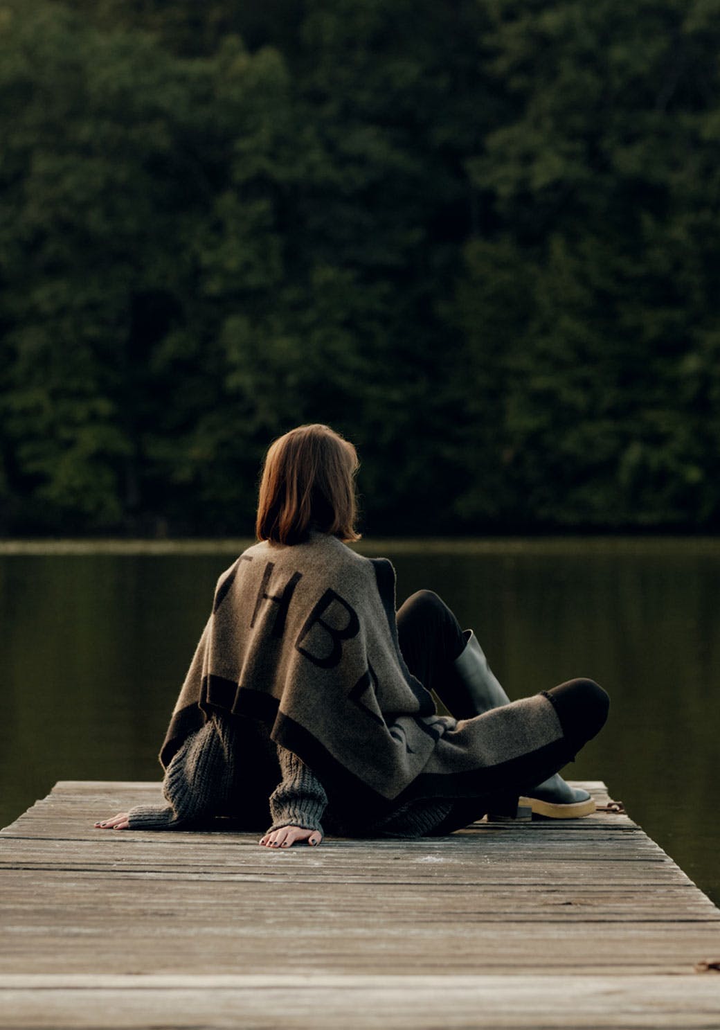 A woman sitting on a dock in front of a body of water