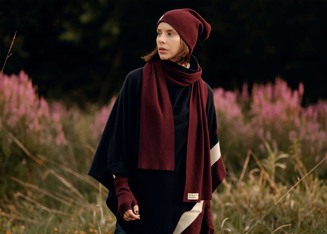 A woman standing in a field wearing a red scarf