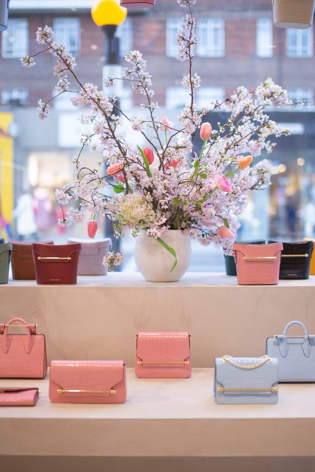 A display of purses and flowers in a window