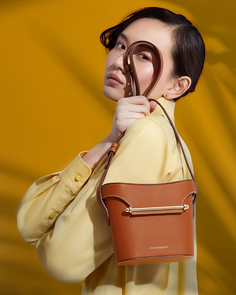 A woman holding a brown purse and looking through a magnifying glass