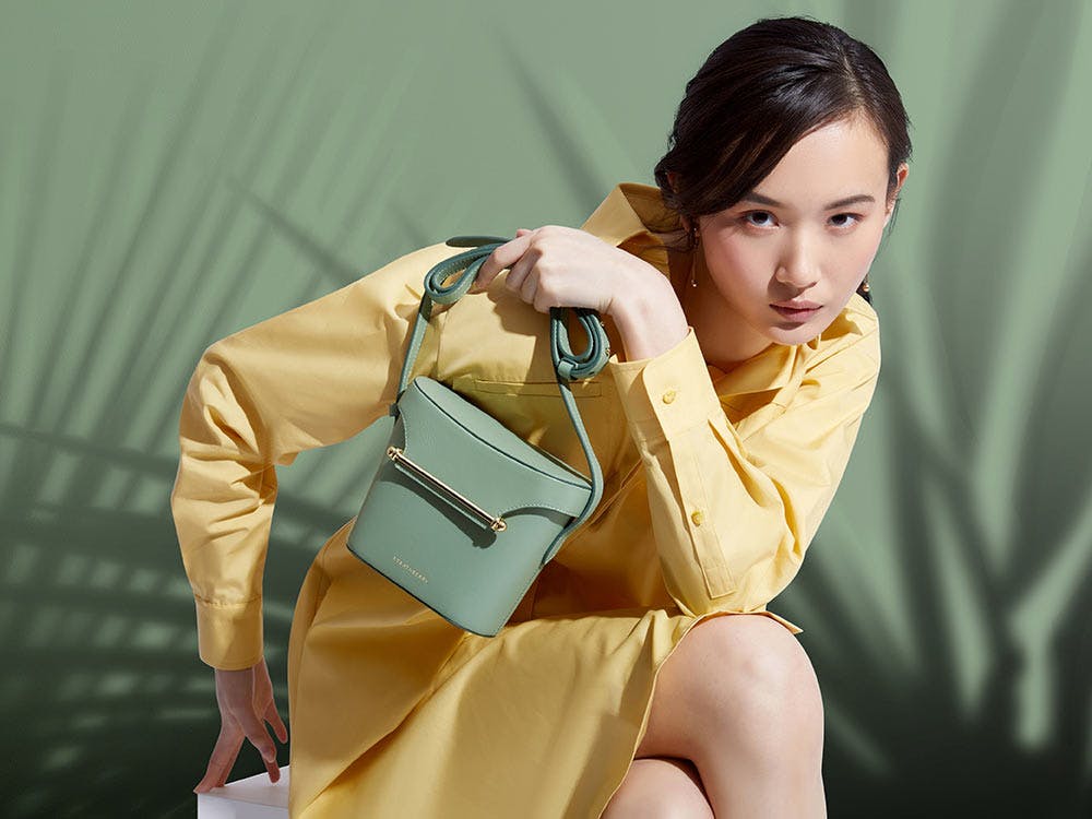 A woman in a yellow dress holding a green purse