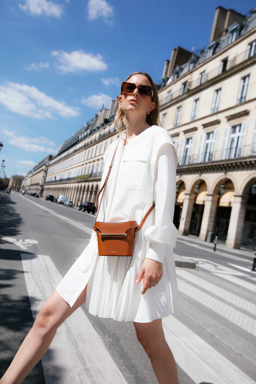 A woman in a white dress is crossing the street