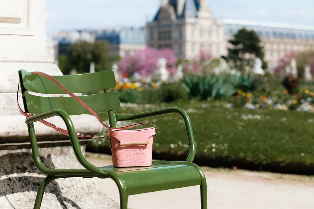 A green chair with a pink flower pot on it