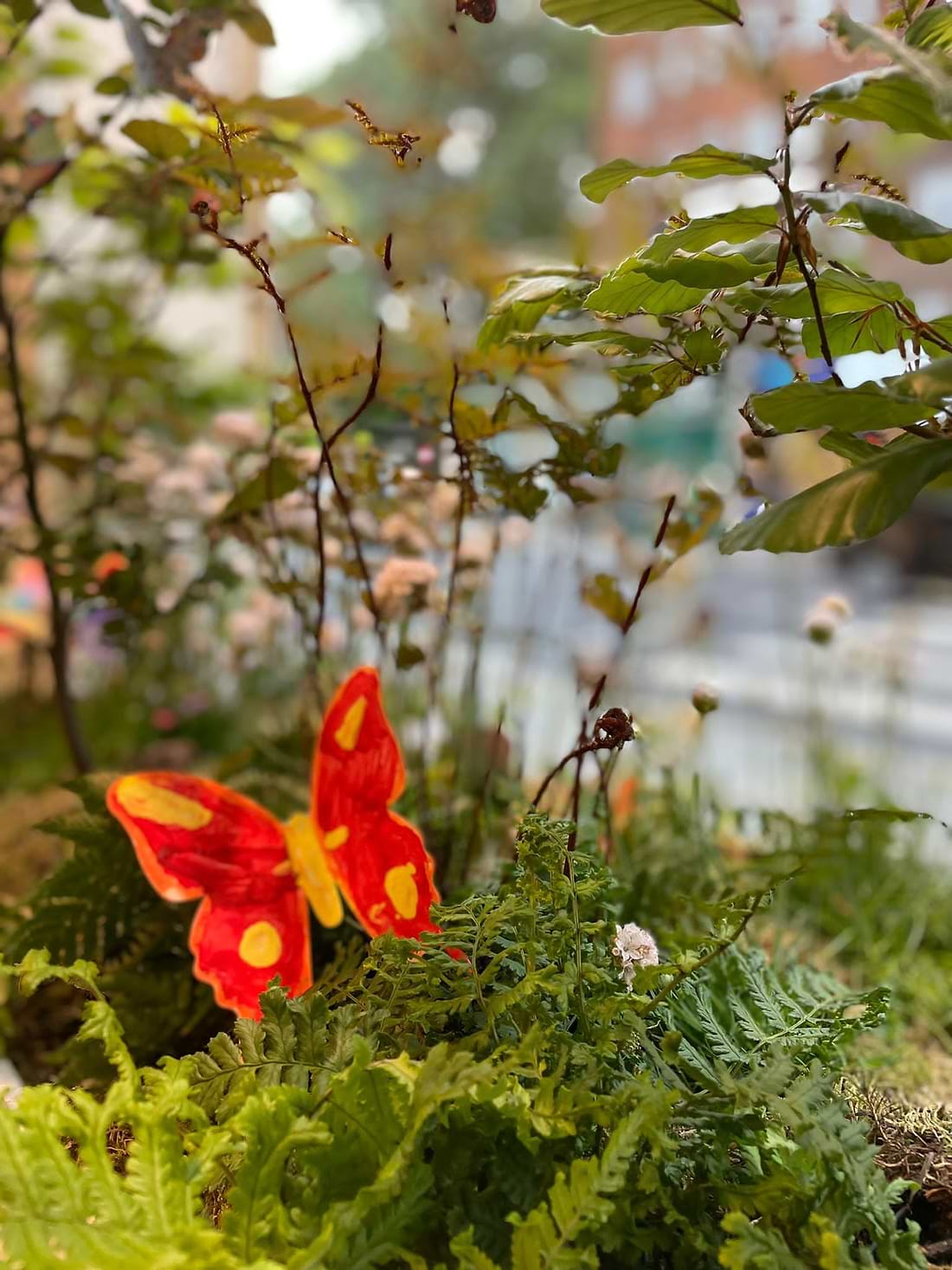 A red butterfly sitting on top of a lush green plant