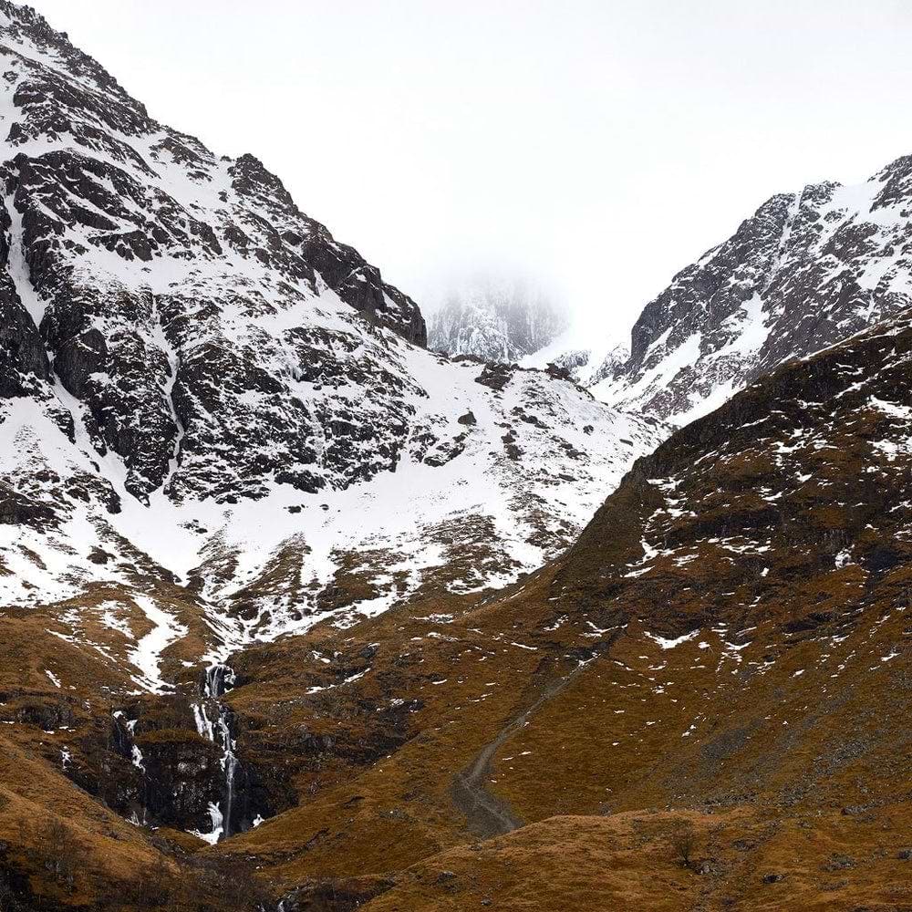 A snow covered mountain with a stream running through it
