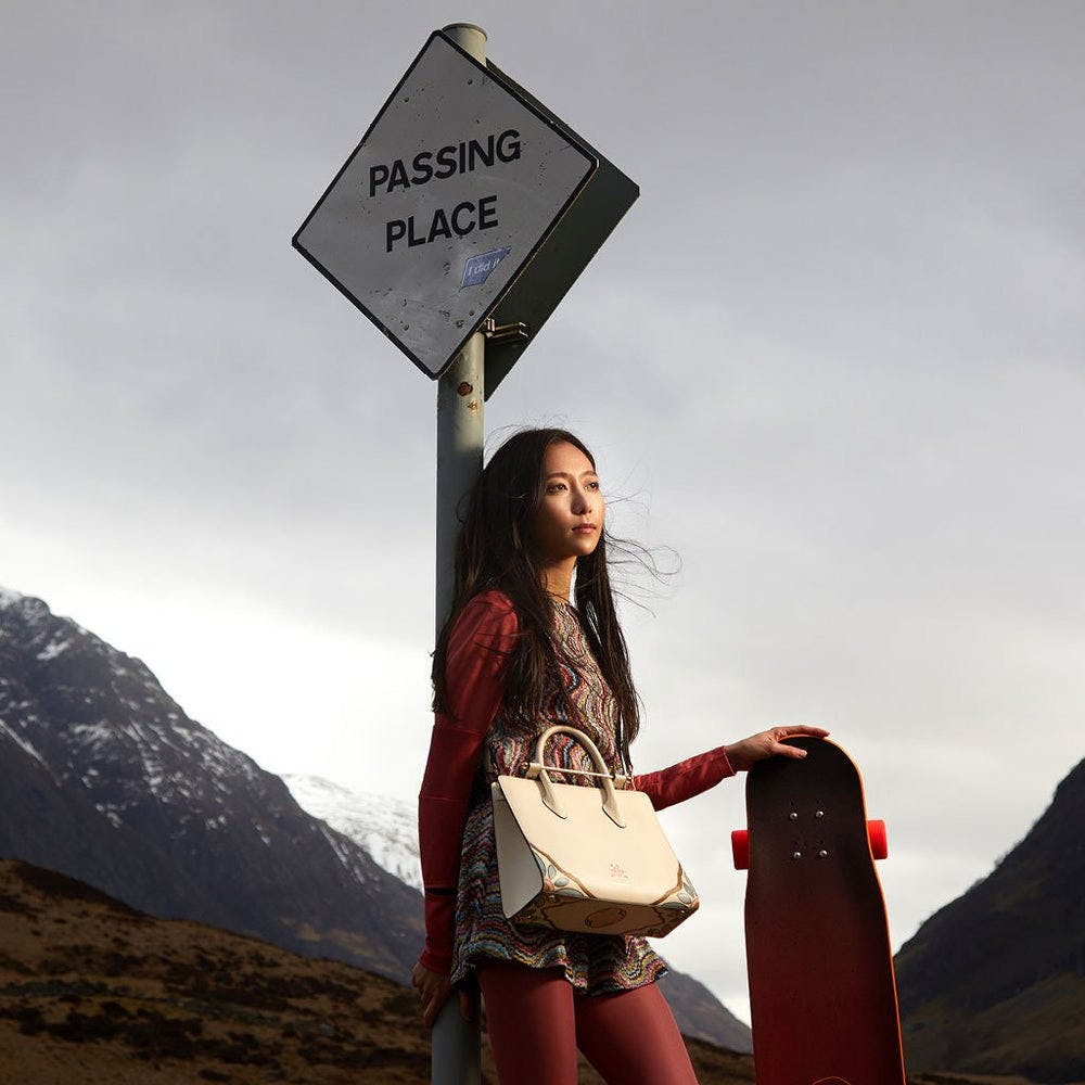 A girl holding a skateboard next to a sign