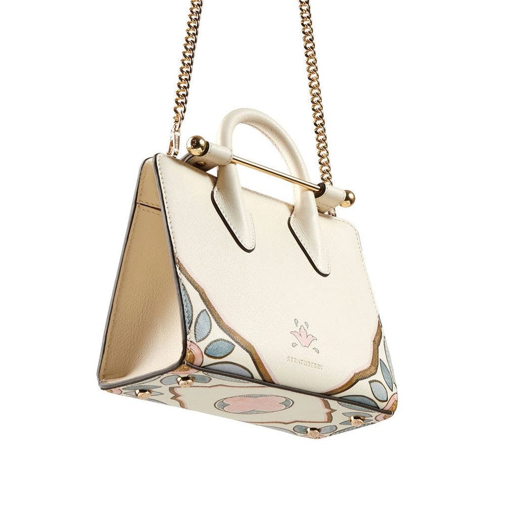 A white purse with a gold chain hanging from it