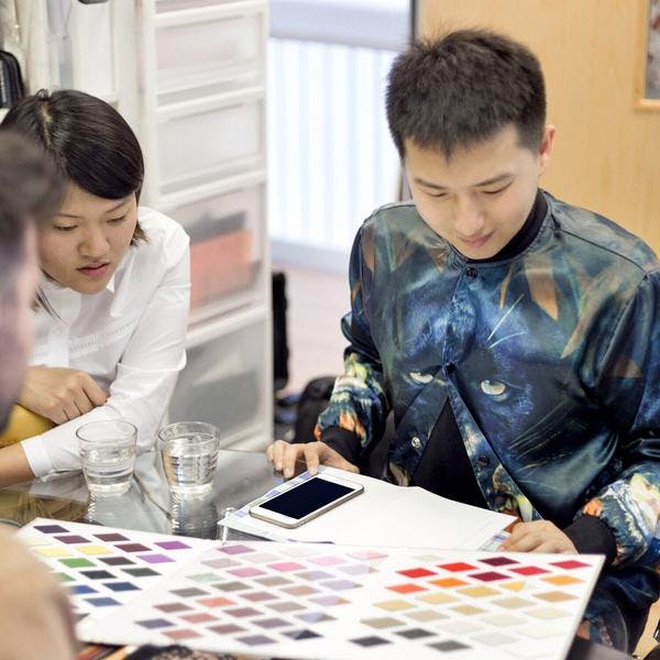 A group of people sitting around a table with a cell phone
