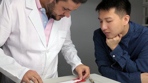 Two men looking at a piece of paper on a table