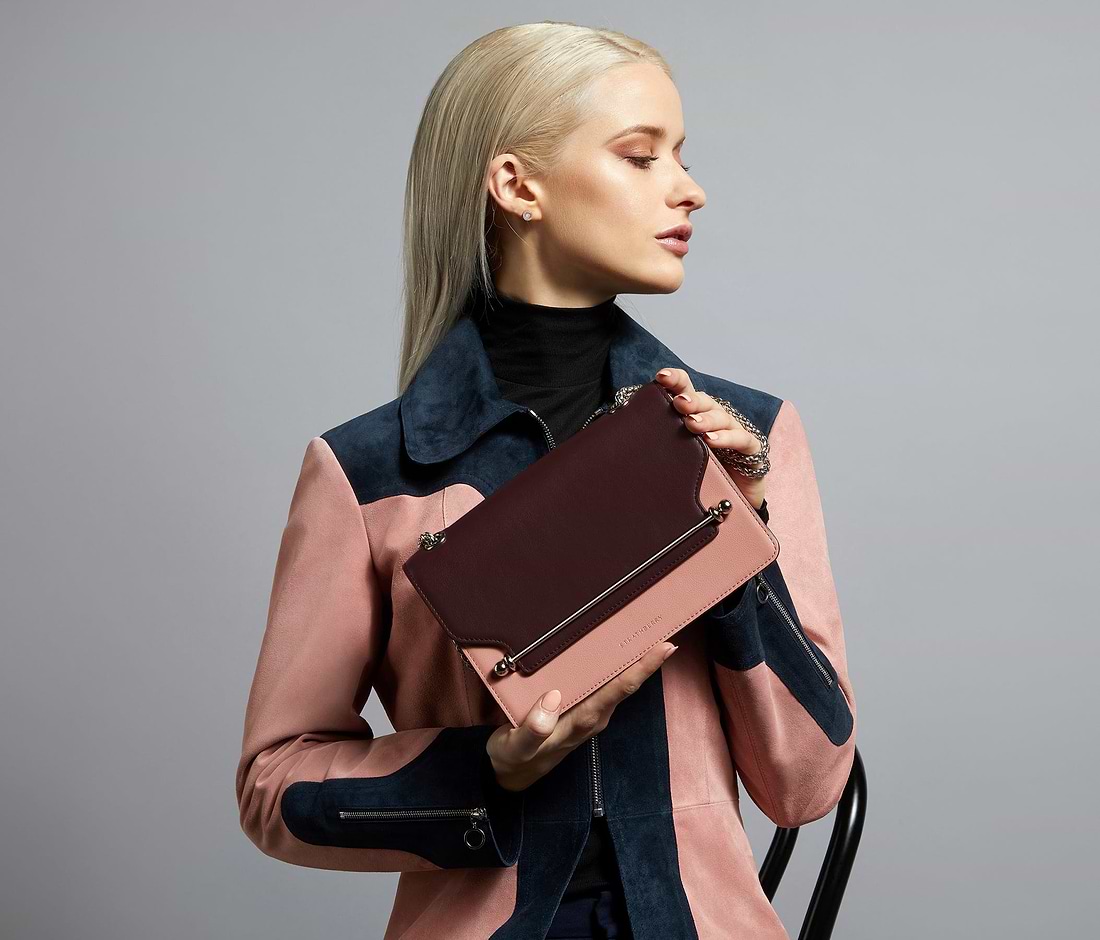A woman in a pink coat holding a brown purse